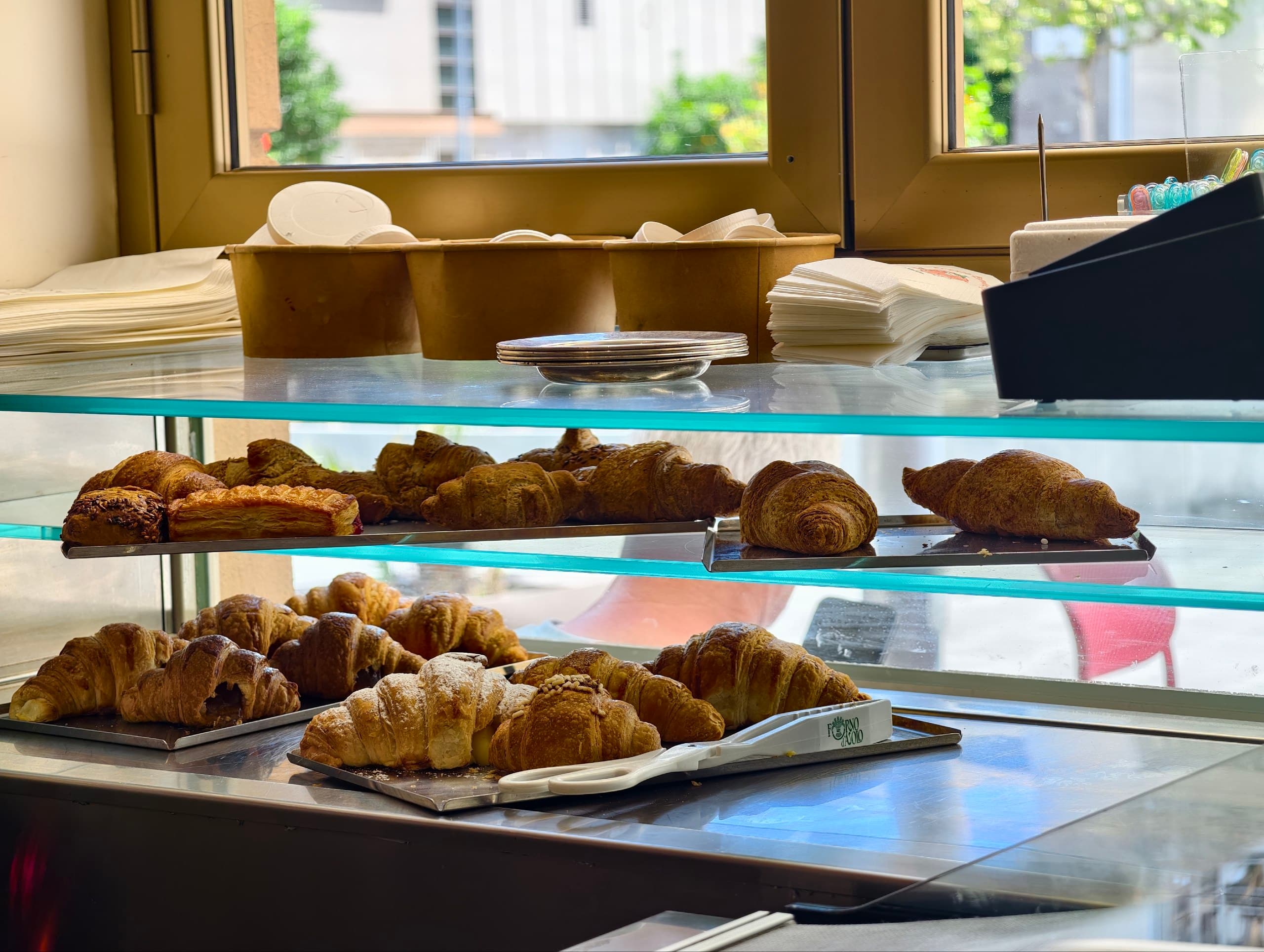 Vetrina di un negozio con croissant e dolci da forno freschi, pronti per essere serviti.