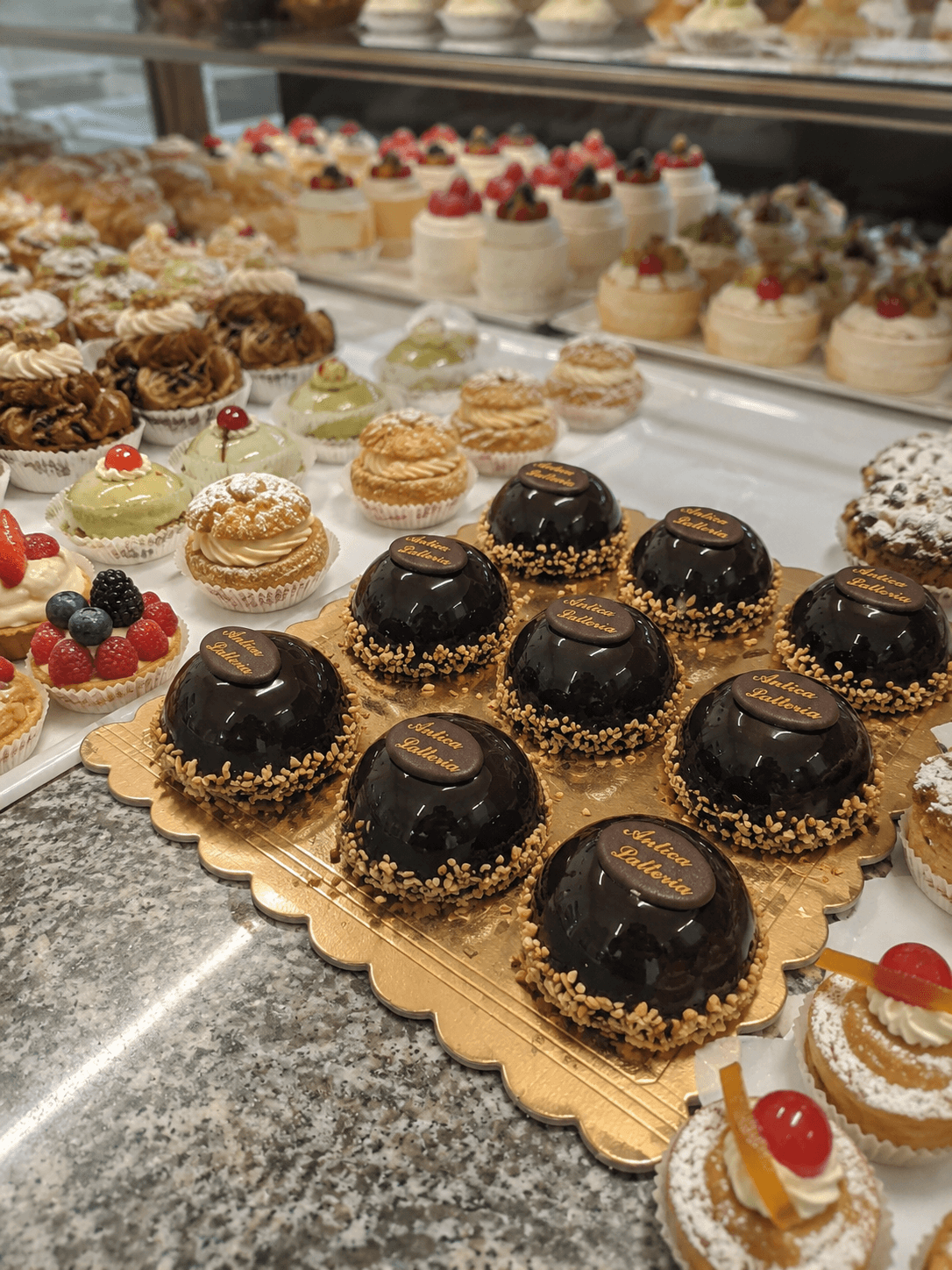 Vetrina di pasticceria con una varietà di dolci, tra cui mousse al cioccolato e pasticcini decorati.