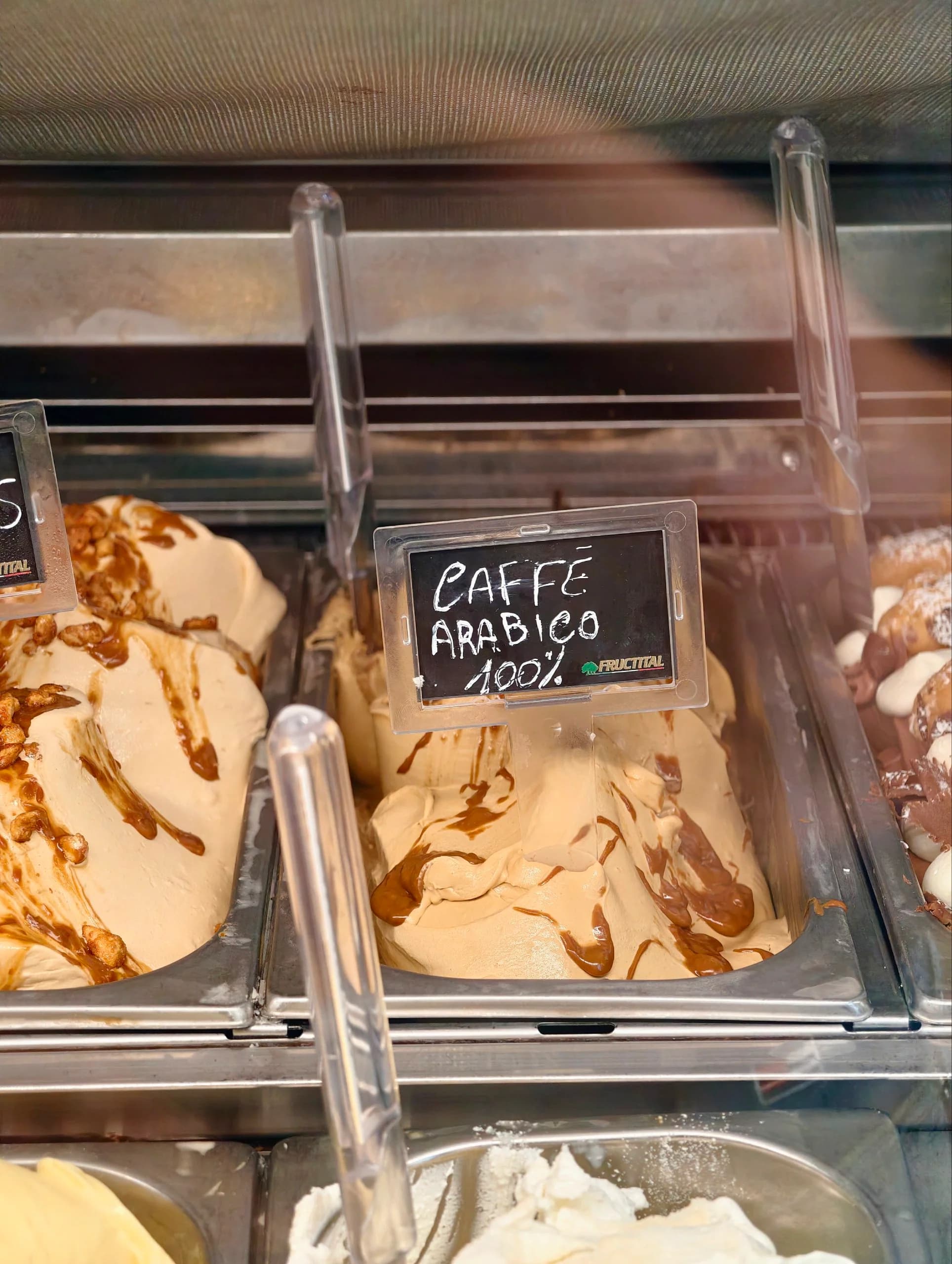 Gelato artigianale al caffè arabico con variegatura al caramello in una vaschetta refrigerata.