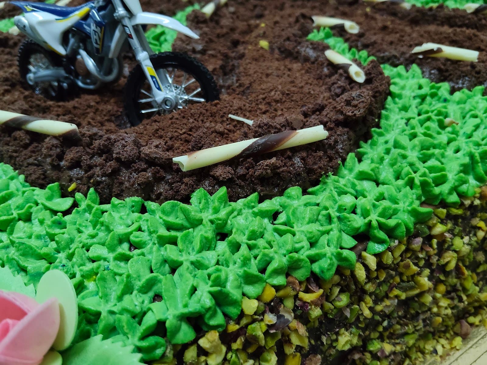 Torta decorata a tema moto cross con crema verde e cioccolato, con una piccola moto in miniatura.